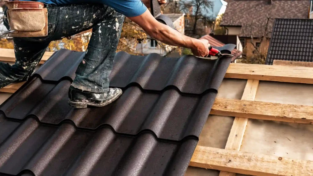 Roofer fastening a metal roof tile with a power tool.