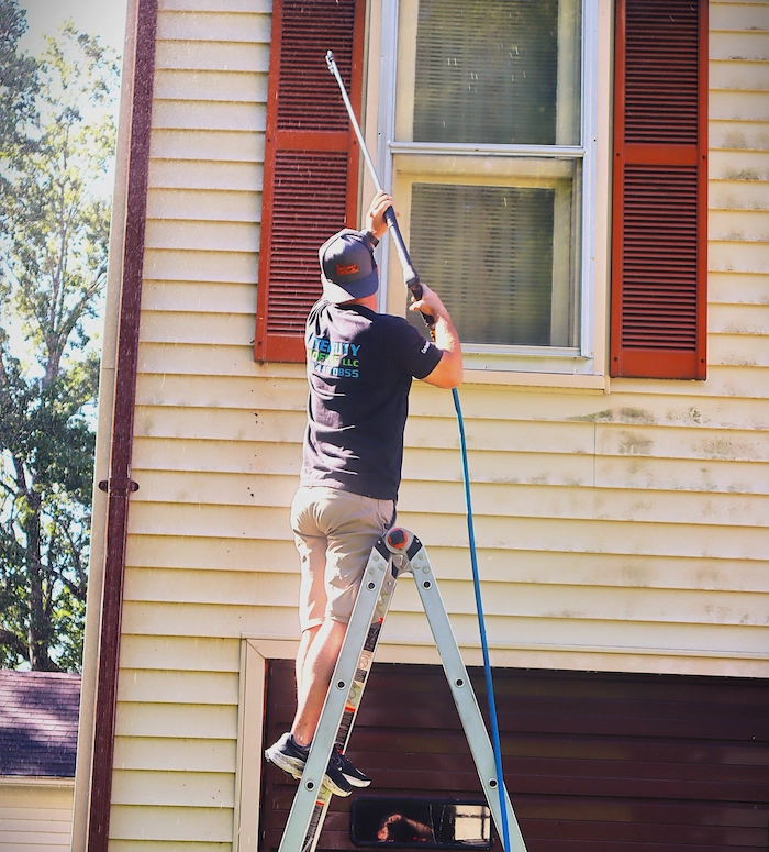 a power washing professional power washing the roof of a residential property