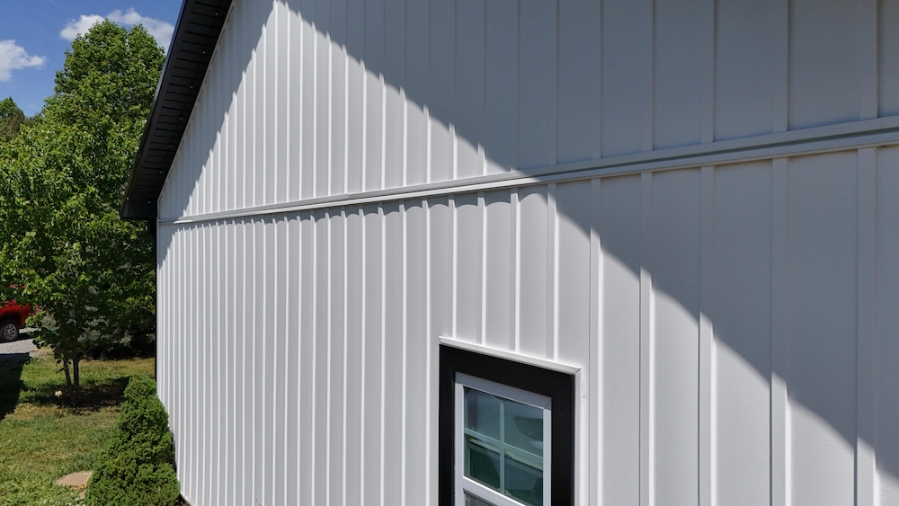 Angular view of a siding installation on a home, showing the shadow lines and a partial view of a dark metal roof.